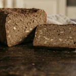 Brezglutenski pumpernickel kruh narezan na rezine na leseni deski.